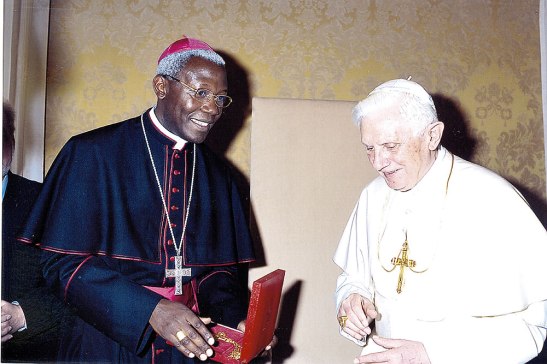 Monseñor Novatus Rugambwa junto al Papa Emérito Benedicto XVI cuando fue nombrado subsecretario del Pontificio Consejo de la Pastoral para los Emigrantes e Itinerantes.